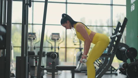 hispanic woman performing barbell bent over row. fitness woman training bent-over row aka bent over row aka barbell row. train your back muscles with a barbell while standing in a tilt