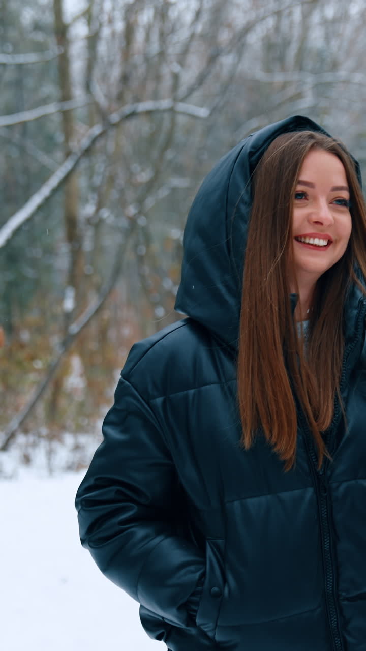 Happy relaxed woman with long brunette hair walks by the park in winter. Smiling lady with coffee cup in hands on the walk. Vertical video