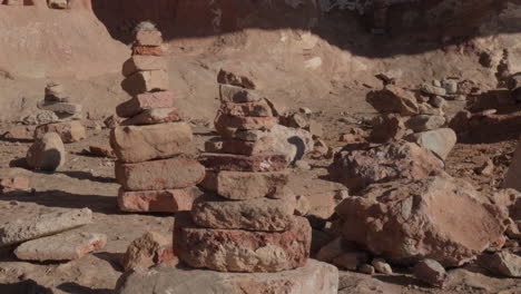 precision and balance: hand placing a rock on stone pyramid in a sunny sandy environment