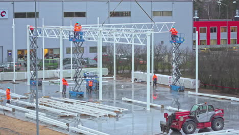 engineers working in aerial platforms at a construction site on a rainy day