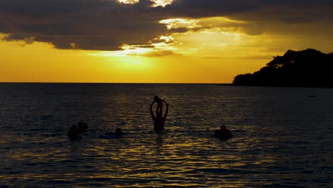 black silhouette of family playing in the sea