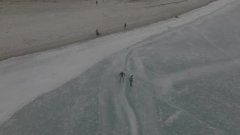 Many-people-go-outside-on-the-frozen-lake-to-ice-skate