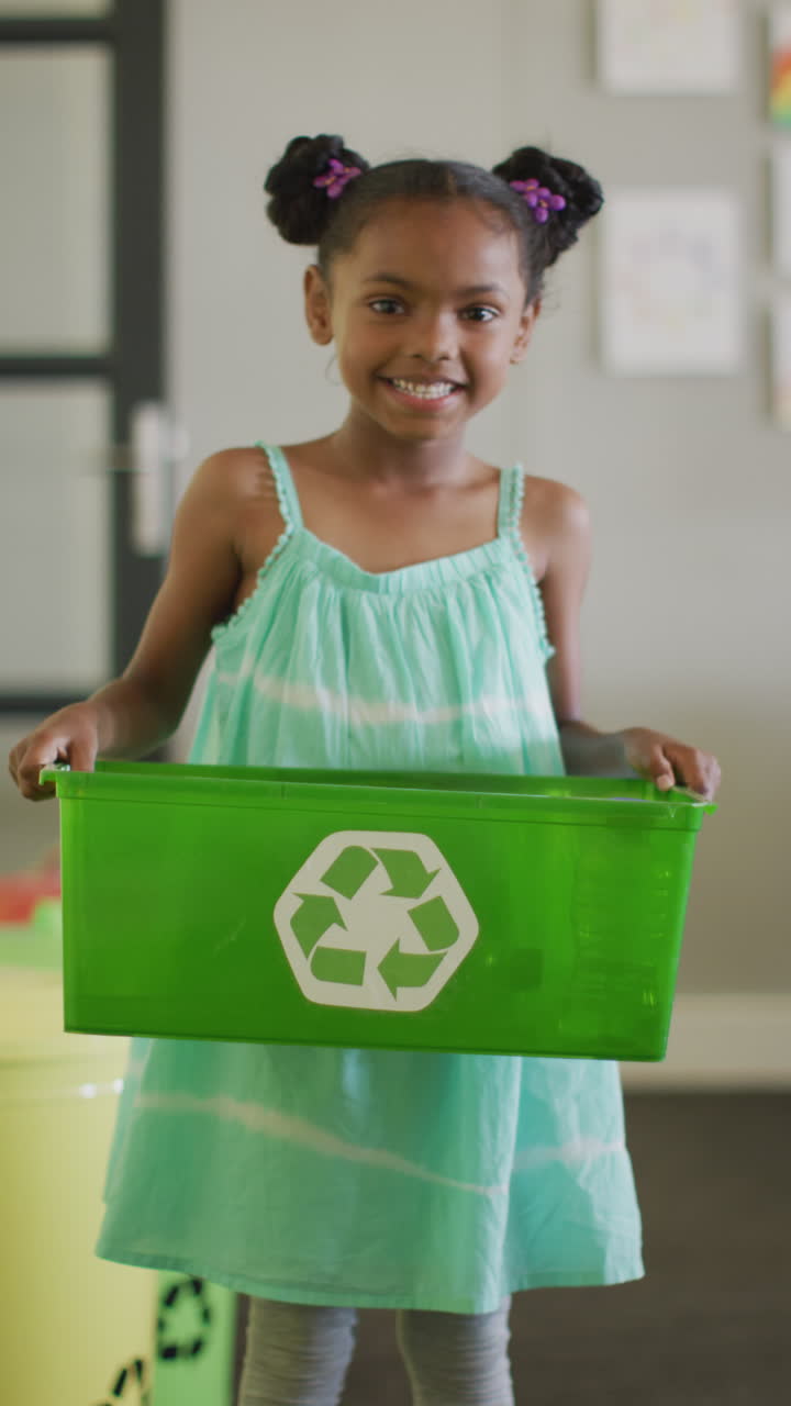 video vertical del retrato de una feliz estudiante afroamericana con una caja de reciclaje
