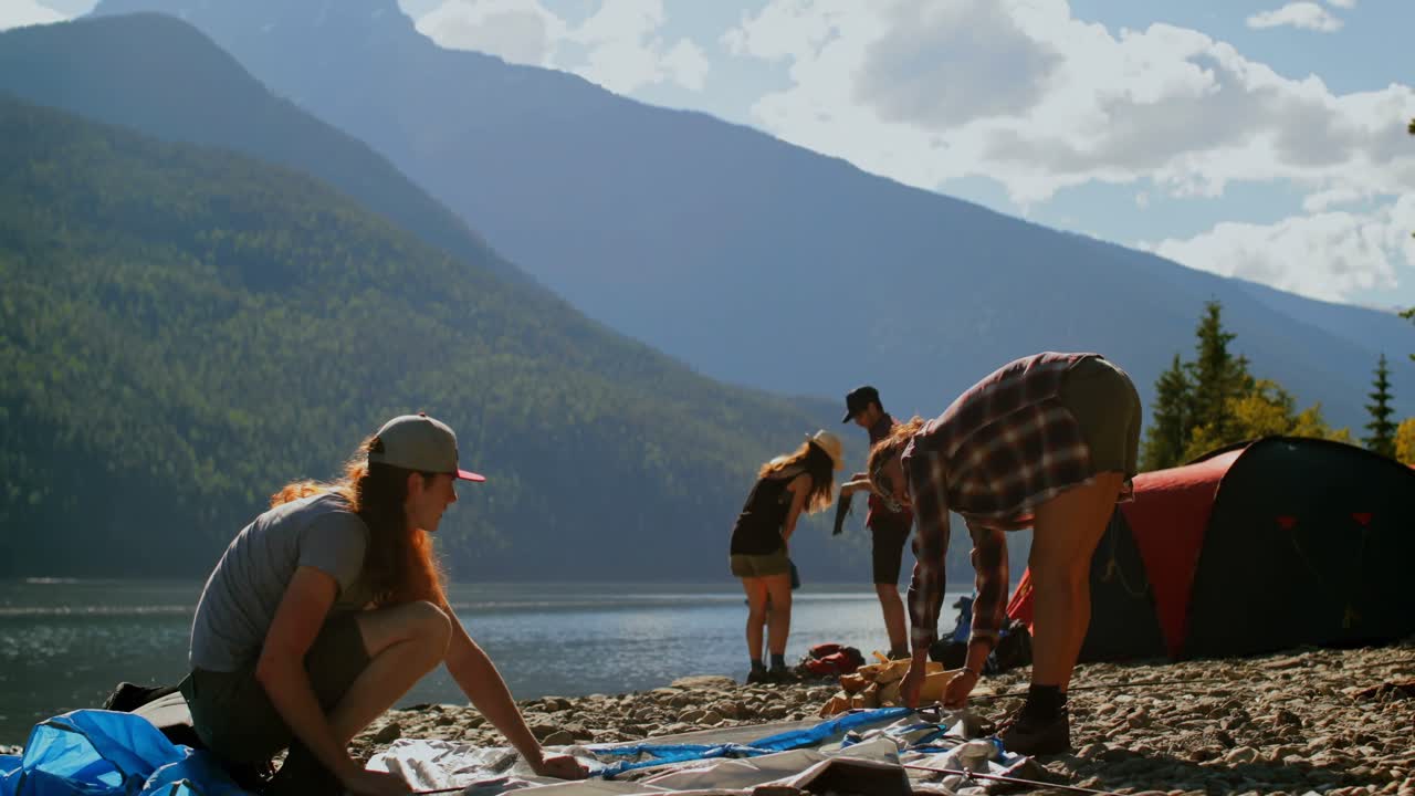 Gruppe turgåere slår opp telt ved elvebredden 4k