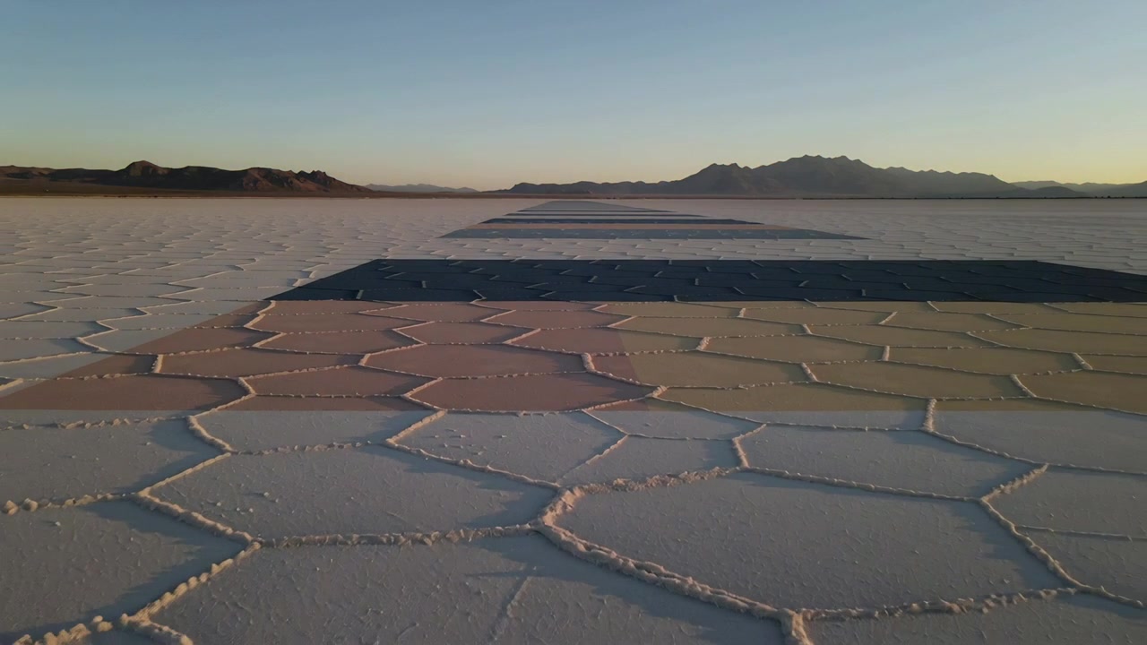 Starting camera sweep, hexagon salt crust moving across flat at sunrise, showing dark strips