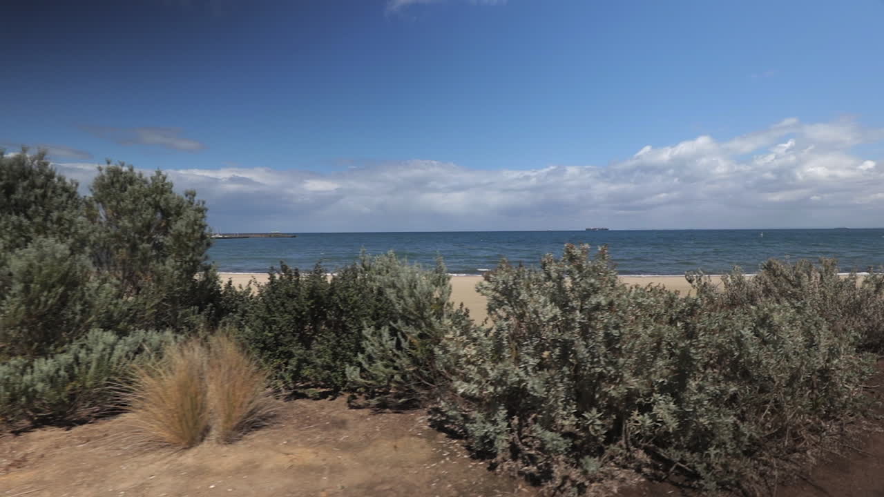 tiro en movimiento de izquierda a derecha que revela la playa de la bahía de hampton, melbourne, australia, día soleado con nubes