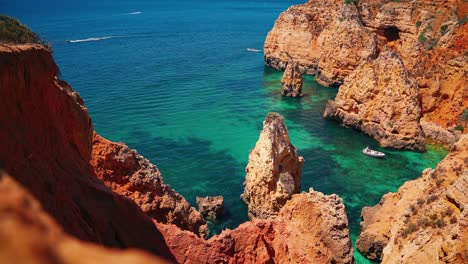 cinemagraph / seamless video loop of a beautiful seaside bay close to praia da marinha, faro and lagos at algarve in portugal with blue and turquoise water and some tourist vacation boats / yacht ships exploring the scenic hidden beaches.