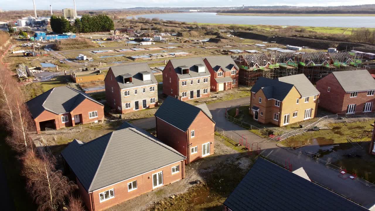 Ufærdig ejendomsudviklingsbyggeplads med rækkehuse ved vandet, luftfoto med nedstigning