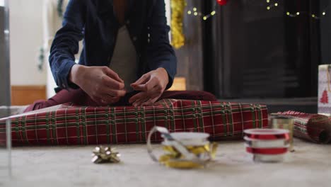 Mid-section-of-woman-wrapping-Christmas-presents-at-home