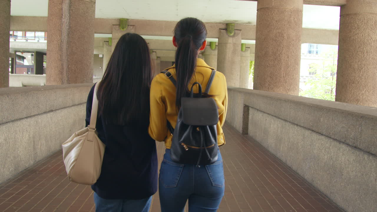 런던 시의 바비칸 센터를 함께 고 있는 두 명의 젊은 여성 친구의 뒷면