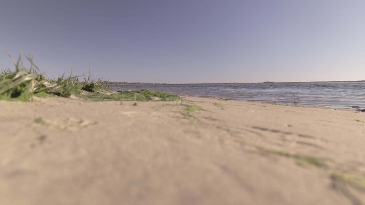 playa de arena vacía, día soleado, vista panorámica baja, espacio para copiar títulos