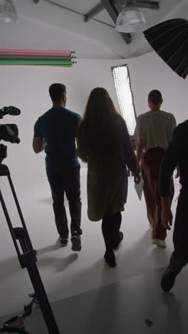 vertical video of film director talking with male and female actors holding scripts rehearsing for shooting movie or video in studio 3