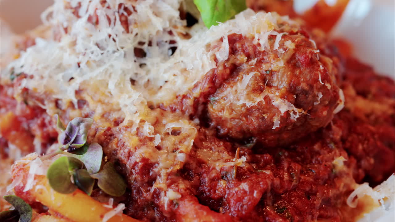 Close up of pasta with meatballs and parmesan on a plate at a restaurant