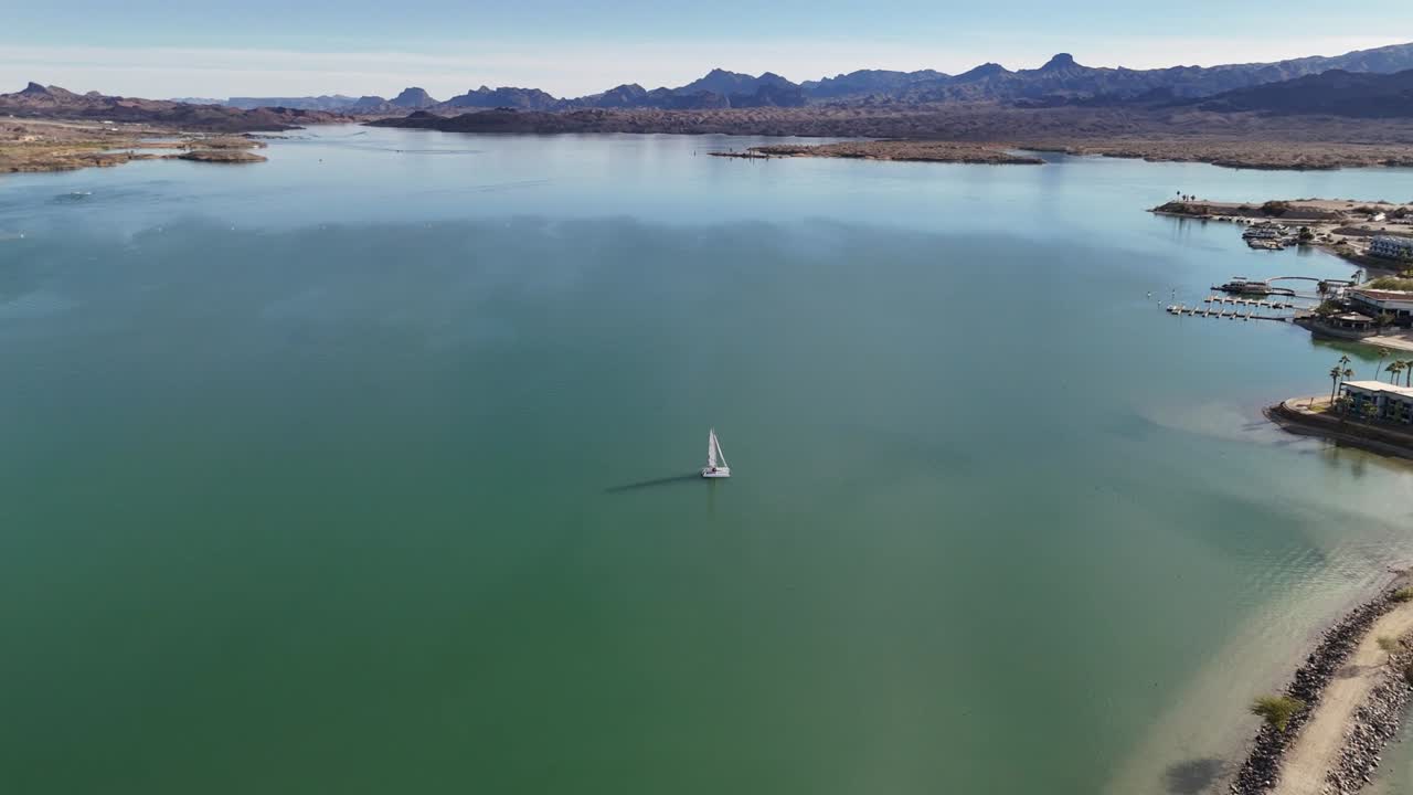 Drone Panning Around a Sailboat on Lake Havasu. Turquoise water, surrounded by mountains