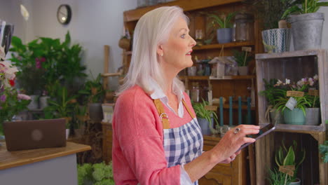 mujer madura propietaria de una floristería que utiliza una tableta digital para recibir pedidos en línea