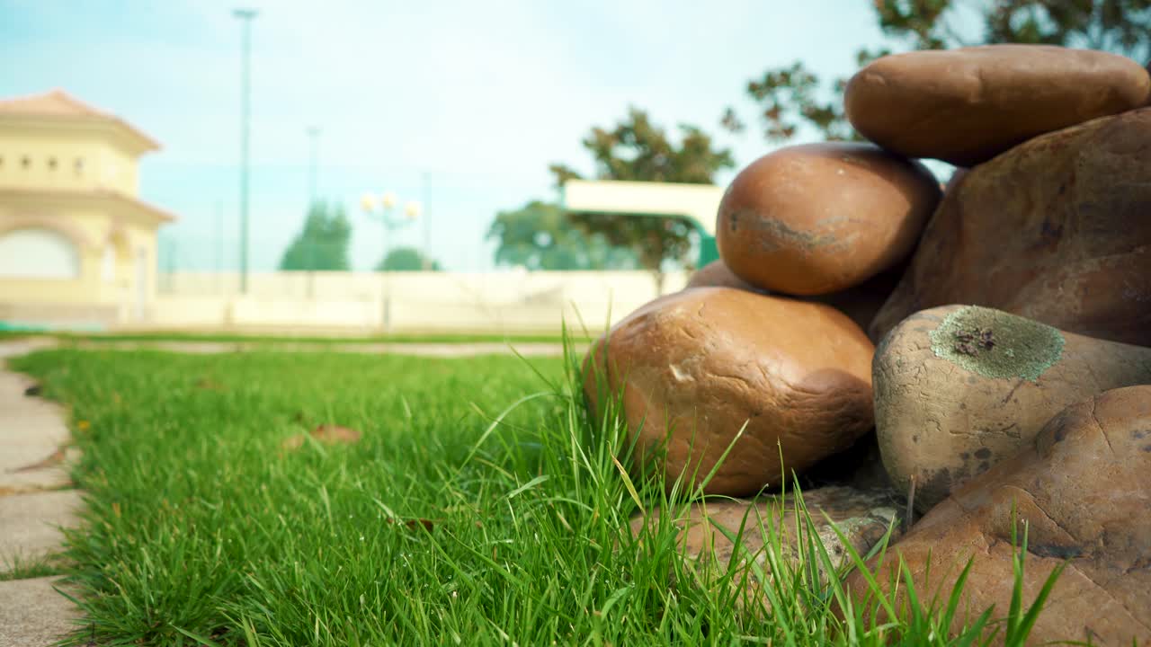 햇빛 아래 잔디 위에 돌 더미, 배경 수영장 근처, 카메라 트럭 샷 4k