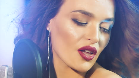 a beautiful woman is singing in audio recording studio on a blue background. close-up