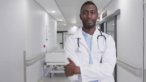 Portrait-of-happy-african-american-male-doctor-in-hospital-corridor,-slow-motion