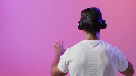 Video-De-Un-Hombre-Birracial-Usando-Auriculares-Vr-Sobre-Fondo-Rosa-Y-Morado