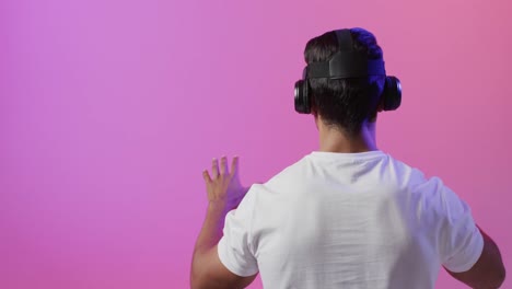 video of biracial man using vr headset on pink and purple background