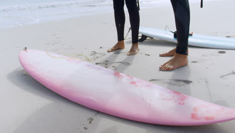 surfer couple standing near the surfboards 4k