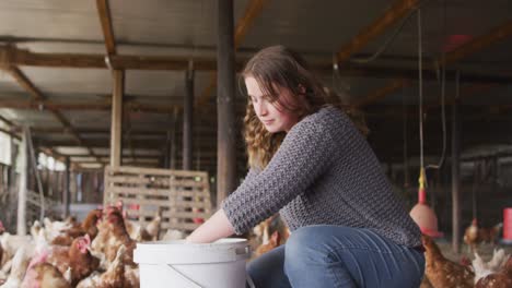 Happy-caucasian-woman,-working-on-farm,-feeding-chickens