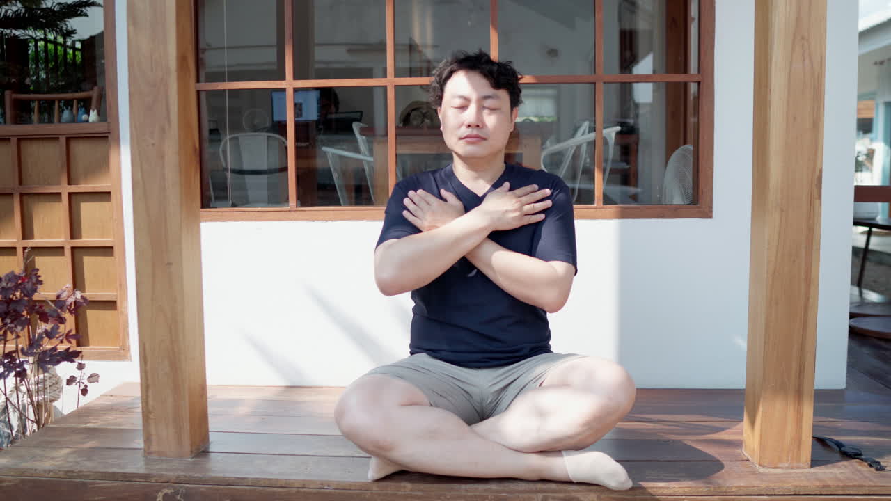 Asian man do breathing exercise with hands to chest to practice mindful yoga
