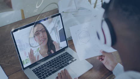 holding technical drawing, person on video call with woman on laptop screen
