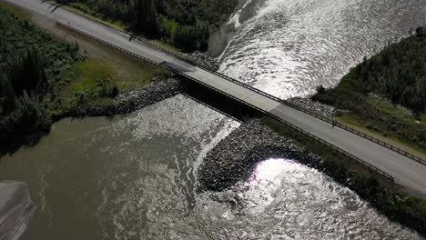 Small-bridge-on-Portage-Glacier-road-over-mountain-river-rapids-in-Portage-valley,-Alaska-USA---aerial