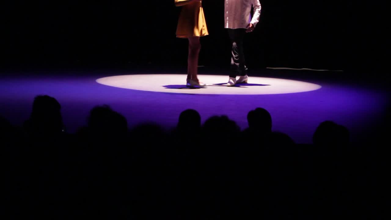 A couple of dancers makes their entrance to the stage in a theater, cinematic light in a theater