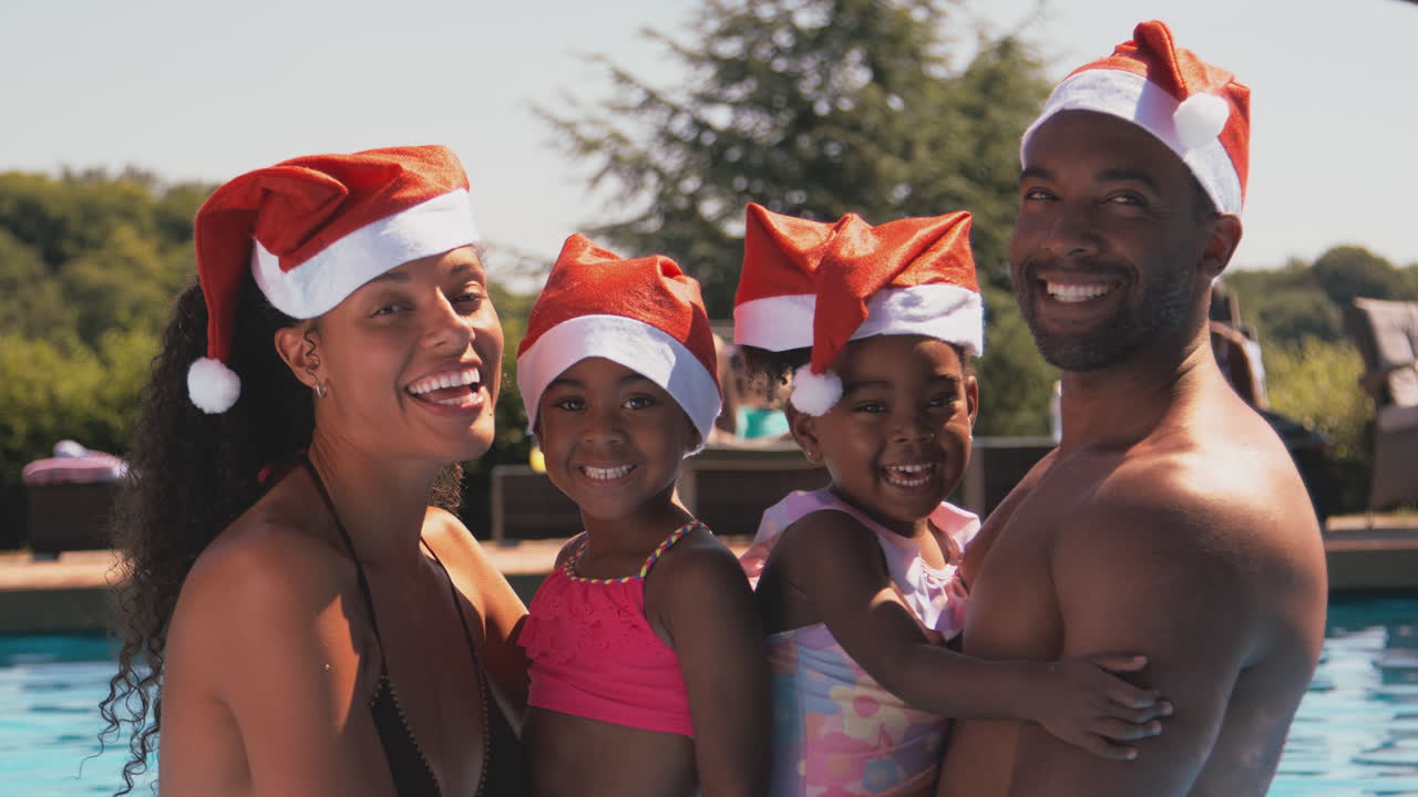 retrato de la familia en las vacaciones de navidad en la piscina con sombreros de santa