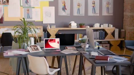 empty animation studio with modern furniture, computers, documents on desks and drawings on the wall