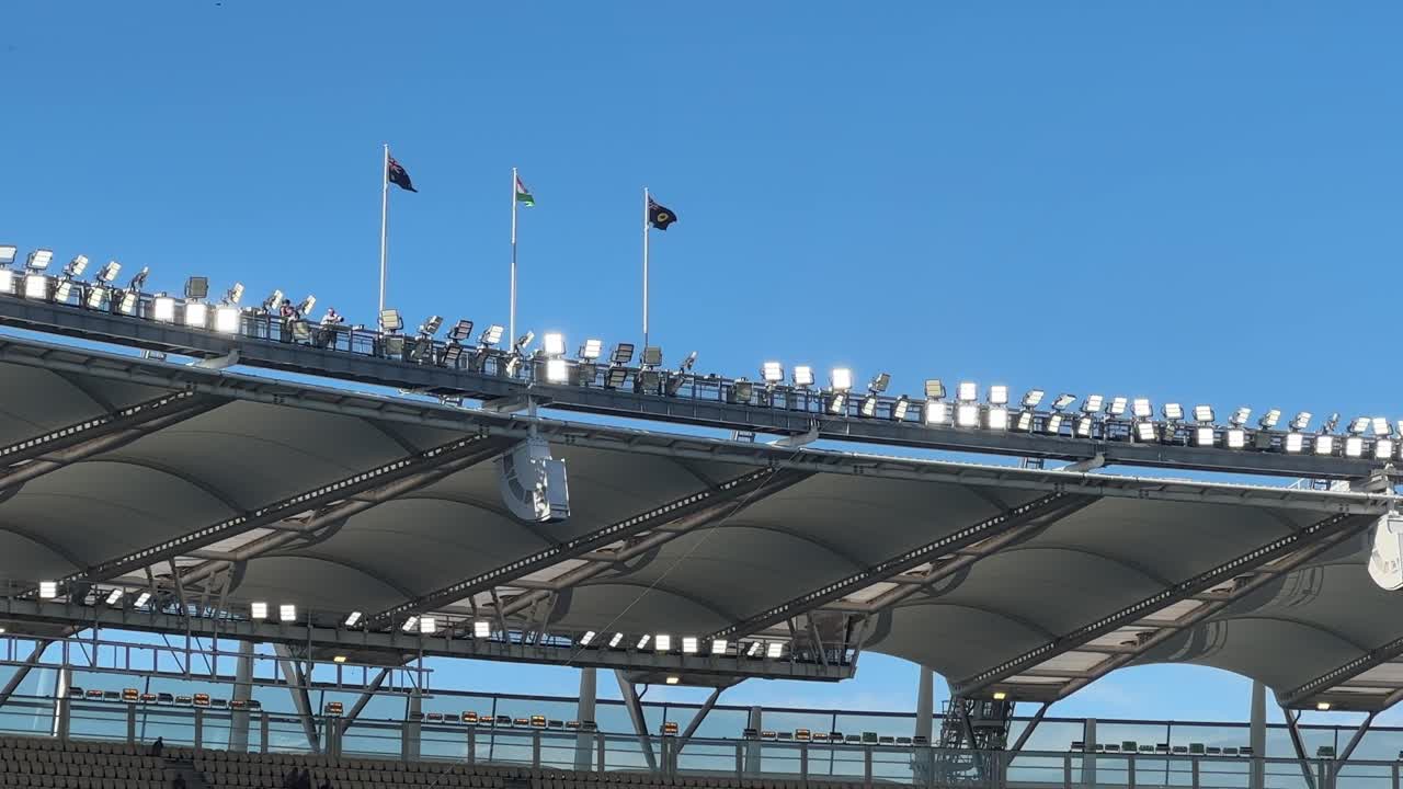 Flags flying atop Optus Stadium Perth arena lights at top