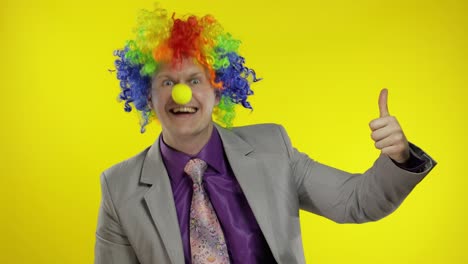 Clown-businessman-entrepreneur-boss-in-wig-show-thumb-up.-Yellow-background