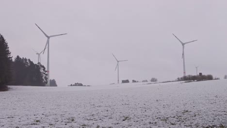 three wind turbines roating in a snowy white winter landscape