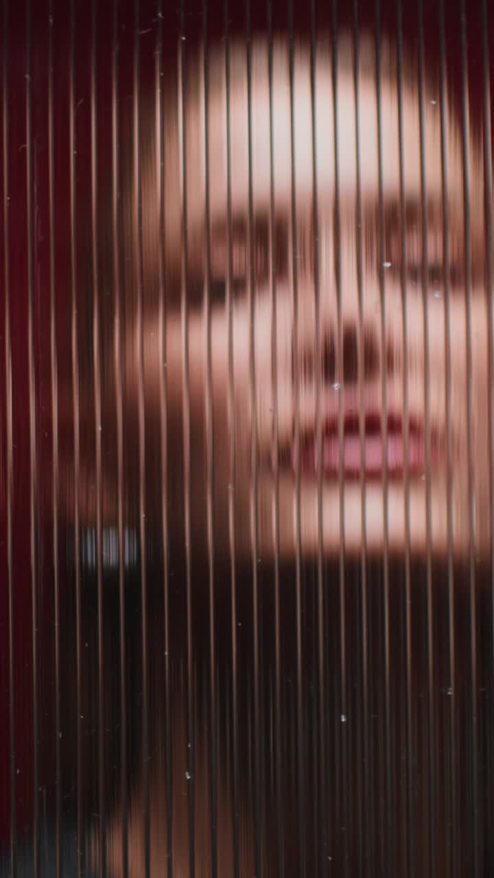 el rostro de la mujer reflejado a través del vidrio ondulado