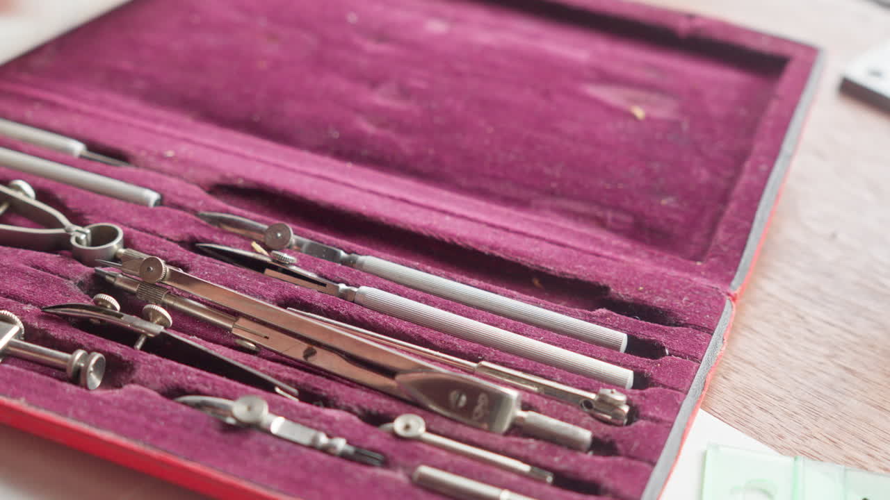 Close POV shot of a hand selecting a metal instrument, emphasizing tactile precision and careful tool choice in design tasks