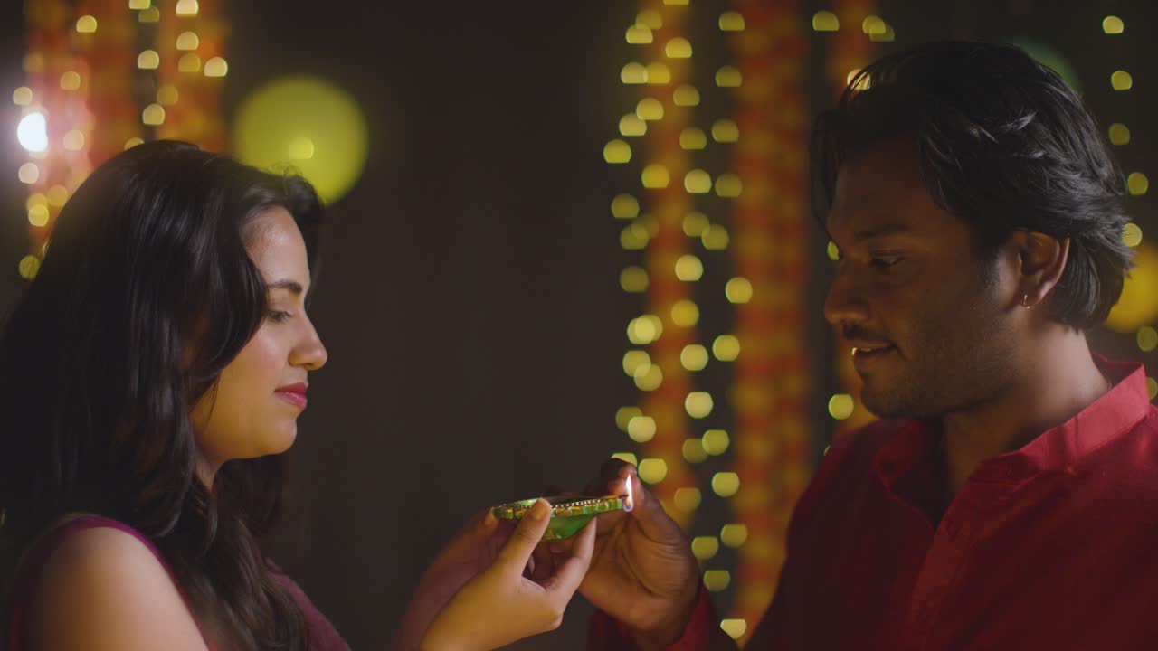 Ritratto di una giovane coppia che celebra il festival di Diwali accendendo una lampada a olio Diya 1.
