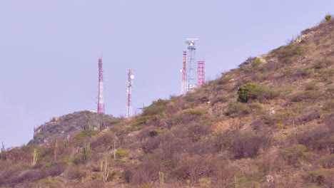telefoto de las antenas de la torre de teléfonos celulares oscurecidas por la colina cubierta de follaje seco