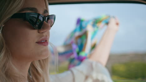 girl hipster driving auto with scarf swayed by wind in hand close up. road trip