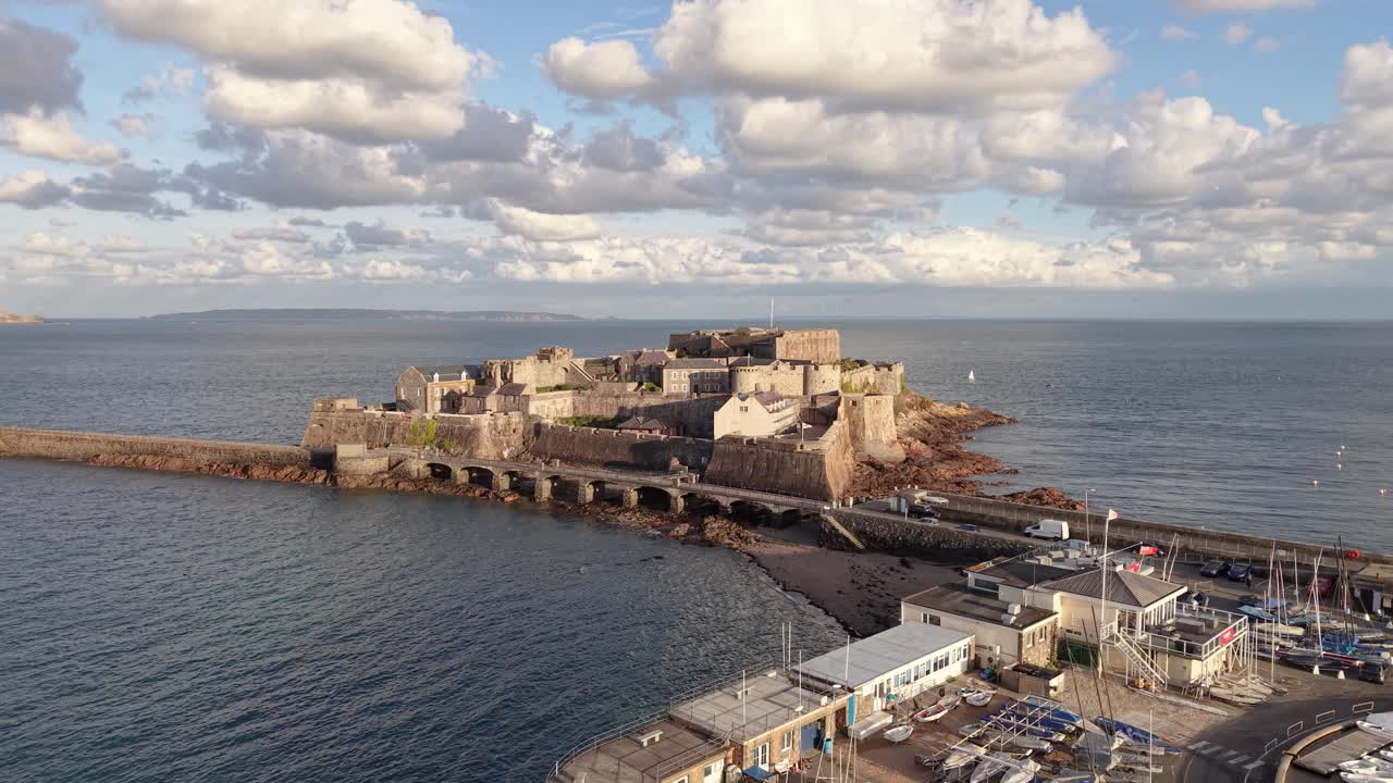 Close low circling drone footage of Castle Cornet St Peter Port Guernsey with interesting light and moody cloudy sky in afternoon sun