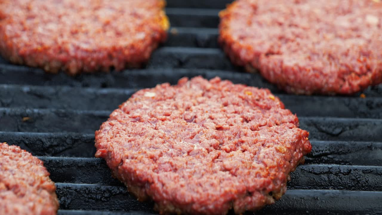 hamburguesas imposibles basadas en plantas de barbacoa en una parrilla eléctrica semiprimer plano que se desplaza hacia arriba y alrededor para revelar numerosas hamburguesas que se doran mientras se cocinan, en el cine 4k