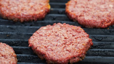 barbecuing plant based impossible burger patties on electric grill semi close up shot panning up and around to reveal numerous patties browning as they cook - in cinema 4k