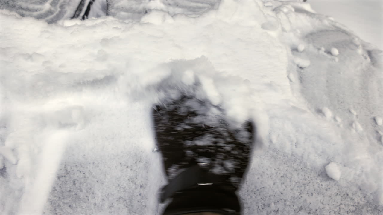 Man with brown leather gloves uncovering the car front window from frozen snow in winter