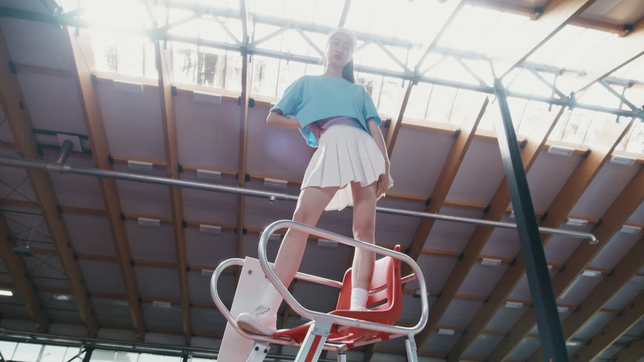 테니스 코트 의자 에 포즈 를 취 하는 젊은 여자