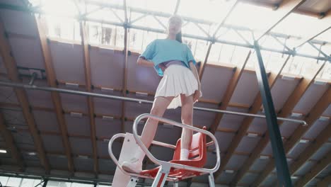 young woman posing on a tennis court chair