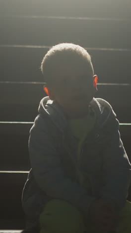 child sitting on cottage stairs silhouette at night. little boy rests alone on steps at country house entrance. abandoned kid waits for parent on pouch