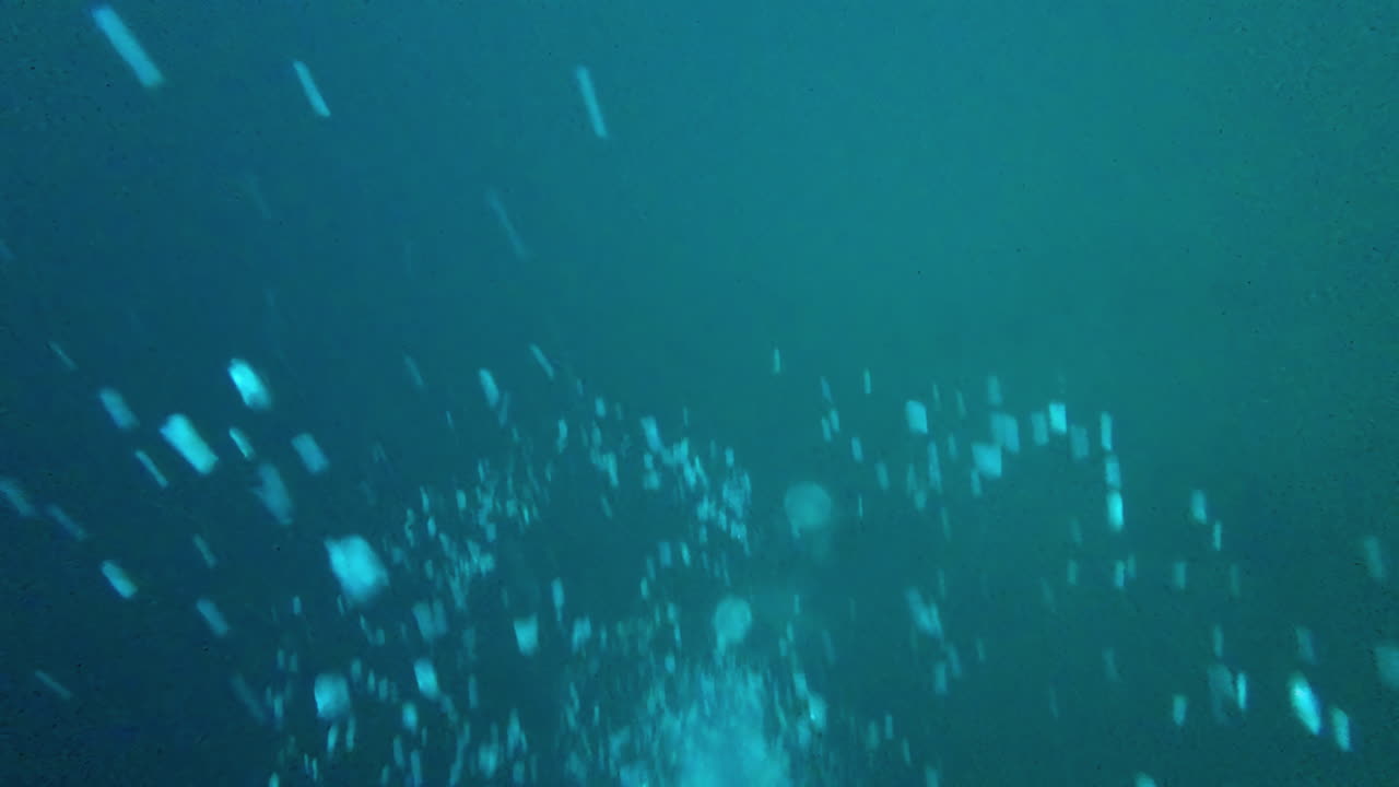 큰 공기 거품이 은 파란 물에서 호수의 표면으로 올라갑니다.