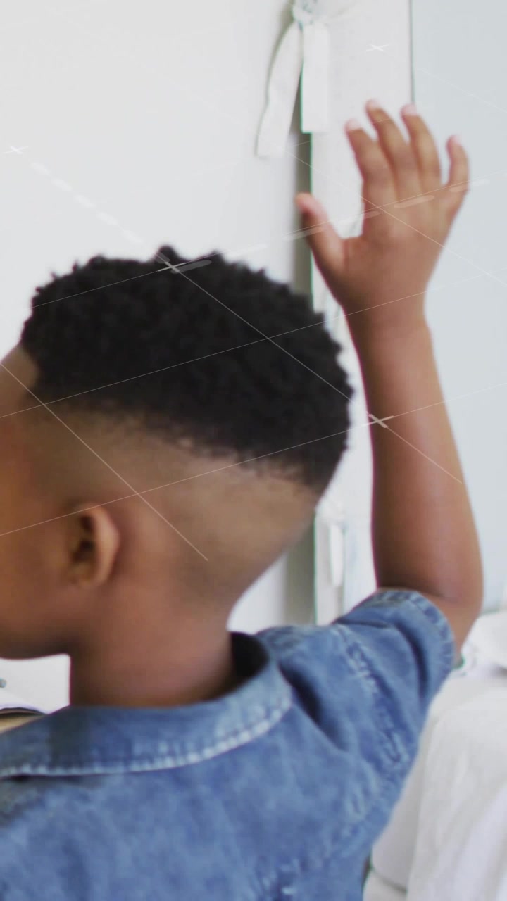 Vertical video: Boy holding right arm up, diagonal sweep crossing causing hand to head for design