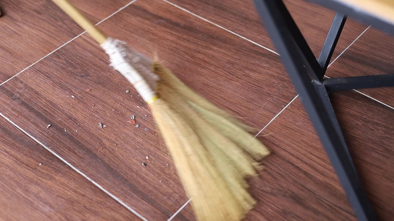 Video zametání rozbitých květinových váz podlahovým koštětem.